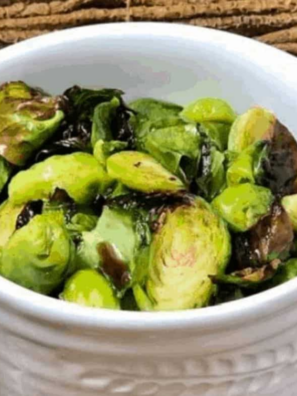 Crispy air fryer honey balsamic Brussels sprouts with caramelized edges tossed in a glossy dark glaze in a white serving bowl