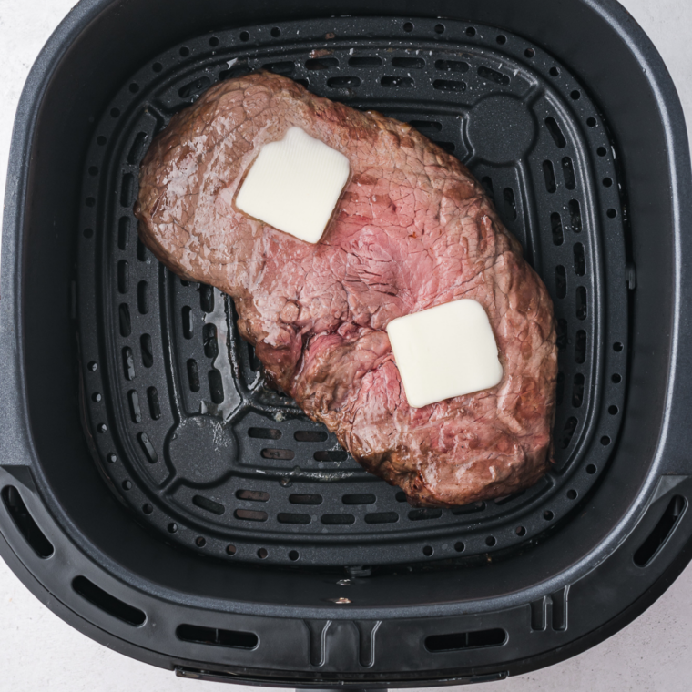 Steaks placed in air fryer basket in a single layer cooking evenly with space between each piece