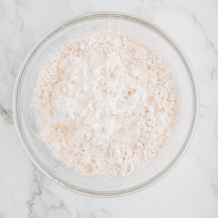 A large mixing bowl filled with pancake batter being stirred with a whisk.