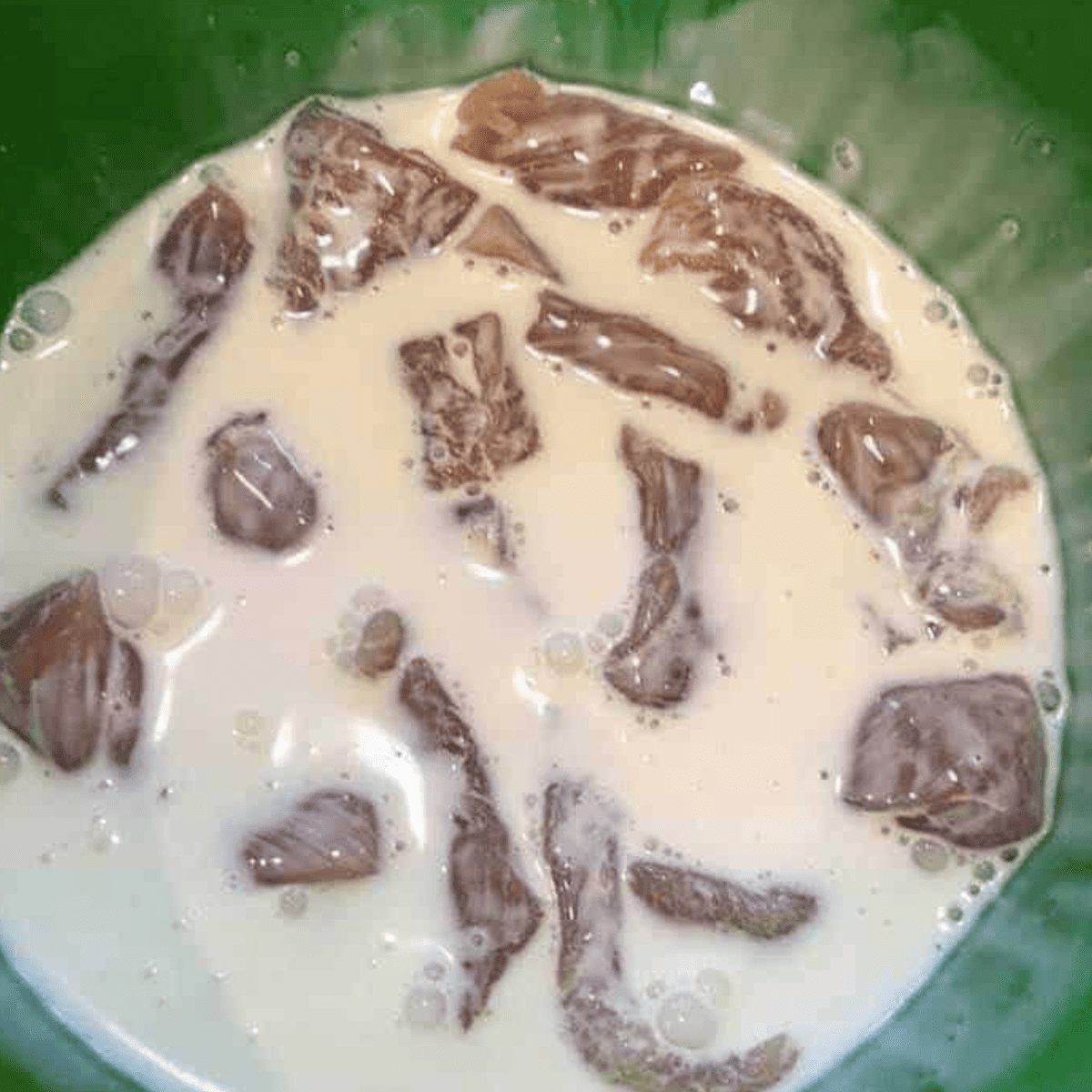 Diced chicken marinating in a bowl with pickle juice and heavy cream before being drained and patted dry with a paper towel.
