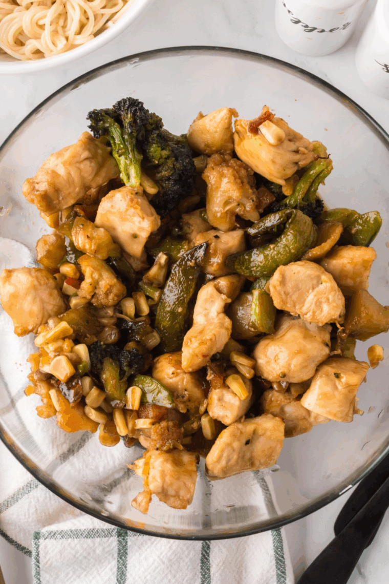 Ninja Foodi chicken stir fry with colorful bell peppers, broccoli, and carrots served in a bowl with savory sauce.