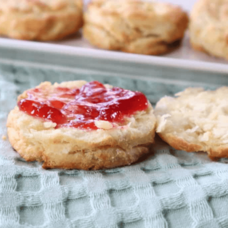 Fluffy, golden Bisquick biscuits cooked in the air fryer, served on a plate with butter.