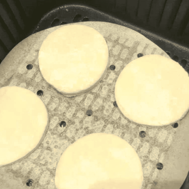 Unbaked Bisquick biscuits placed in the air fryer basket, ready to cook at 330°F.