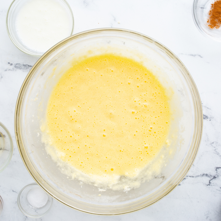 Adding eggs one at a time to the creamed butter and sugar