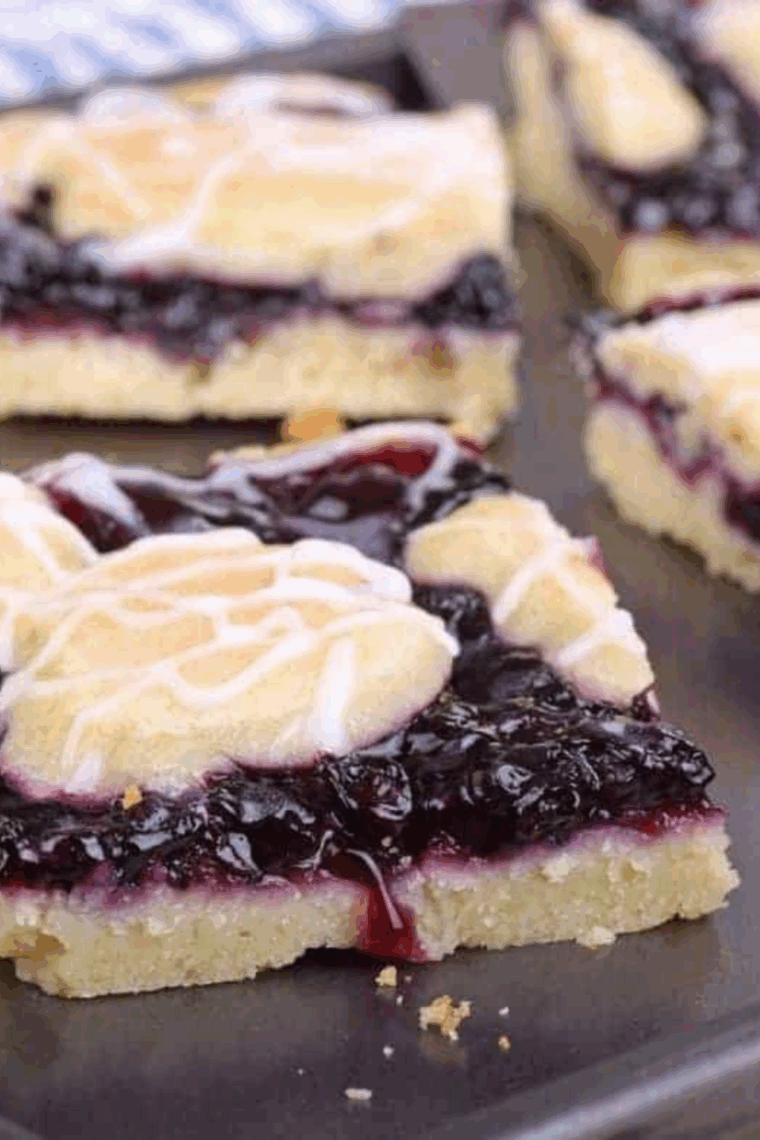 Air fryer blueberry pie bars sliced into squares with a golden crust and thick blueberry filling on a serving plate.