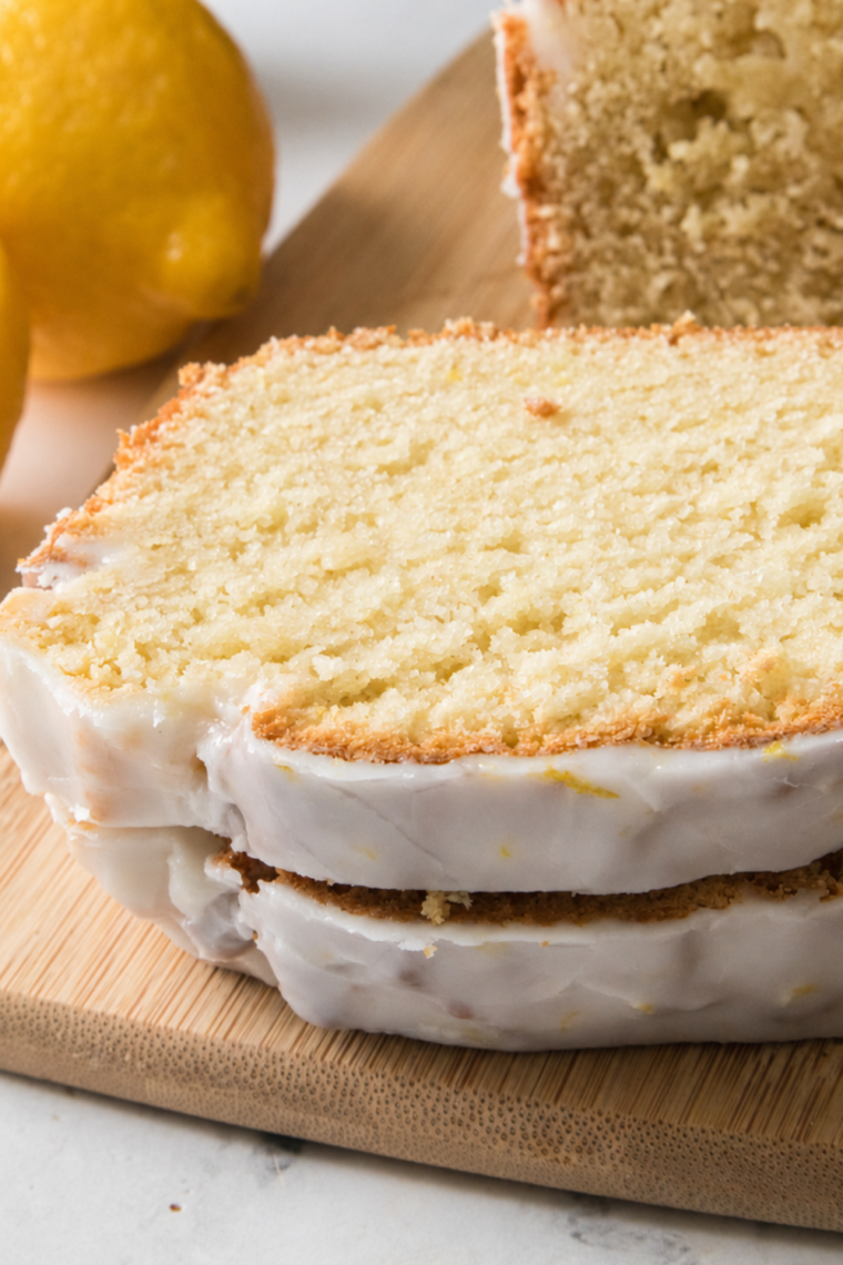 Slice of air fryer lemon loaf leaning against the sliced mini loaf
