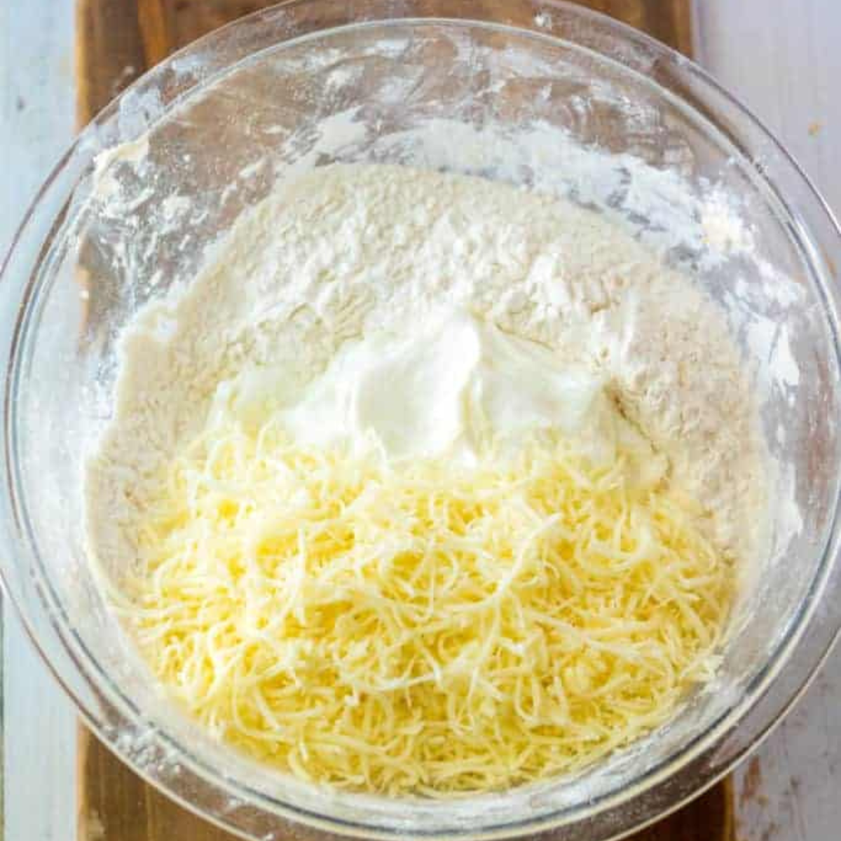 Combine Self-Rising Flour and Greek Yogurt in a mixing bowl.
Image showing self-rising flour and Greek yogurt being mixed together.