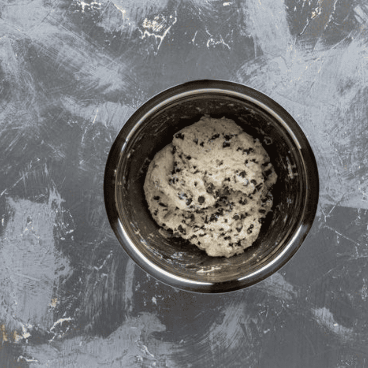 Mixing Dough Ingredients: "Combining flour, sugar, baking powder, and chocolate chips in a mixing bowl to make the bagel dough.
