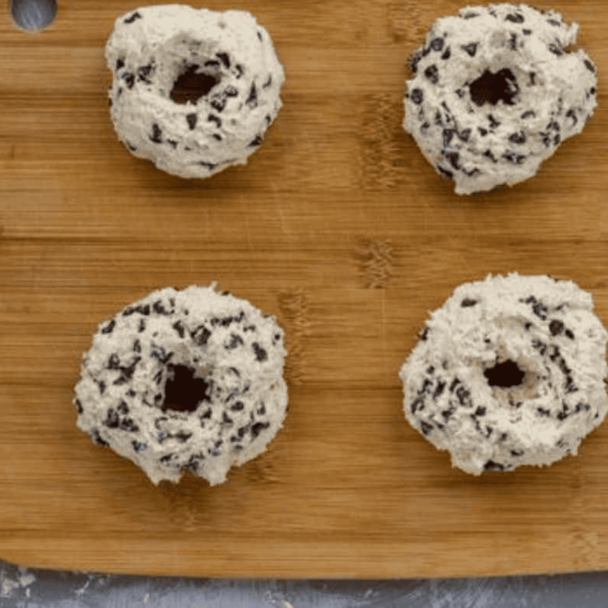 Shaping the chocolate chip bagel dough into round bagel shapes on a wooden cutting board.