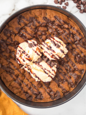 Air fryer chocolate chip cookie pizza sliced into wedges and topped with vanilla ice cream