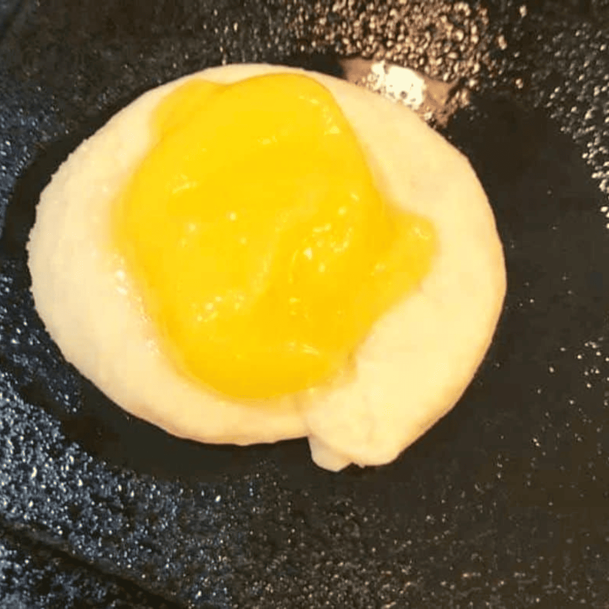 Crescent dough circles on a greased air fryer tray filled with lemon pie filling, ready to air fry at 330°F