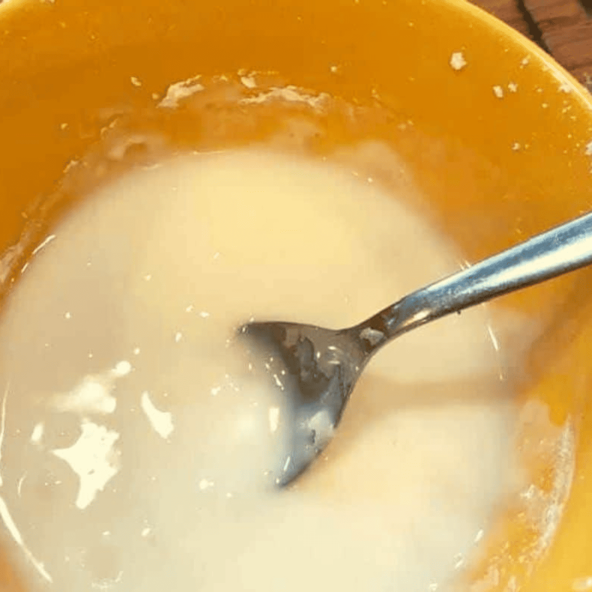 Making icing in a large yellow mixing bowl.