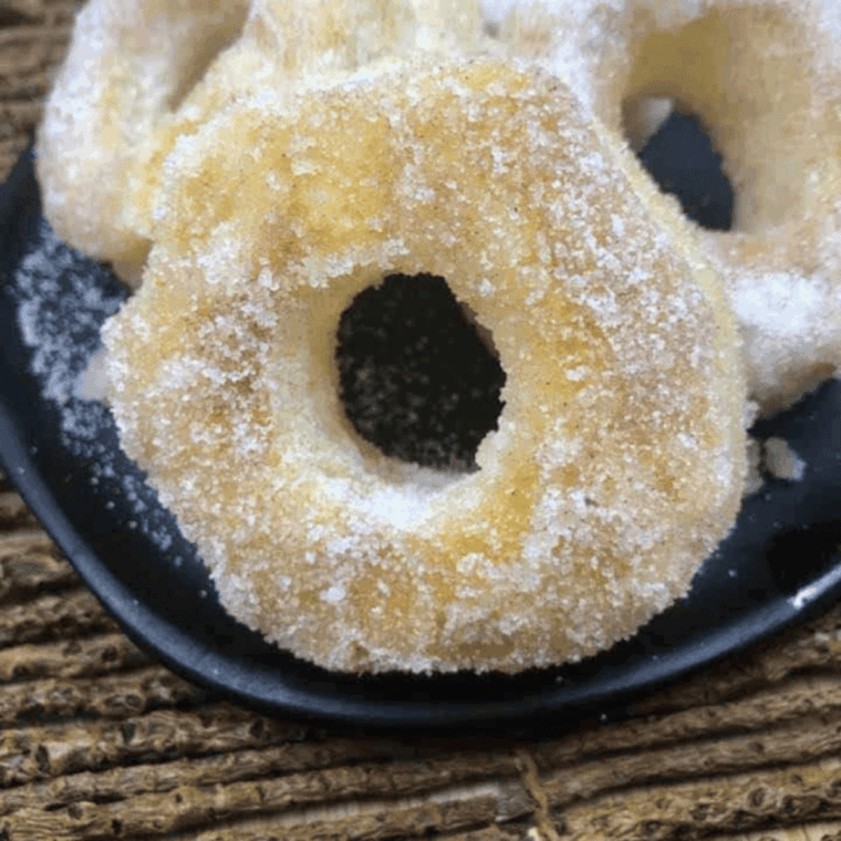 Golden, flaky Air Fryer Puff Pastry Donuts dusted with powdered sugar on a plate.