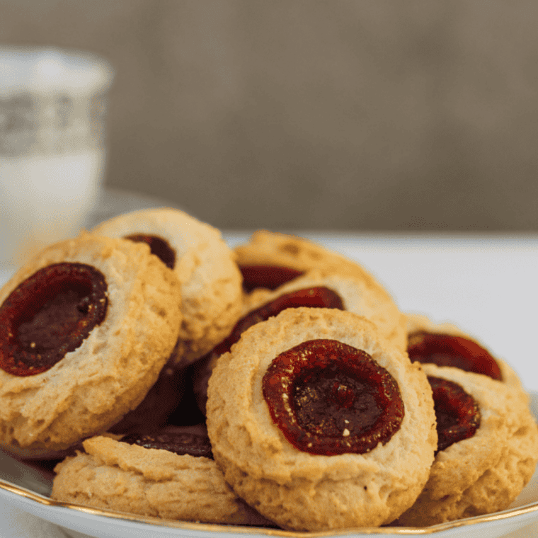 Golden thumbprint cookies fresh from the air fryer, soft and filled with fruity jam centers.
