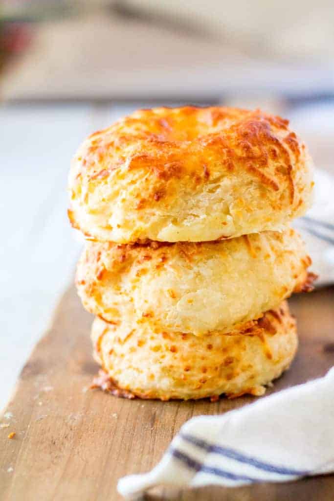 Image showing a stack of golden-brown Asiago cheese bagels with a crispy exterior and melted cheese.