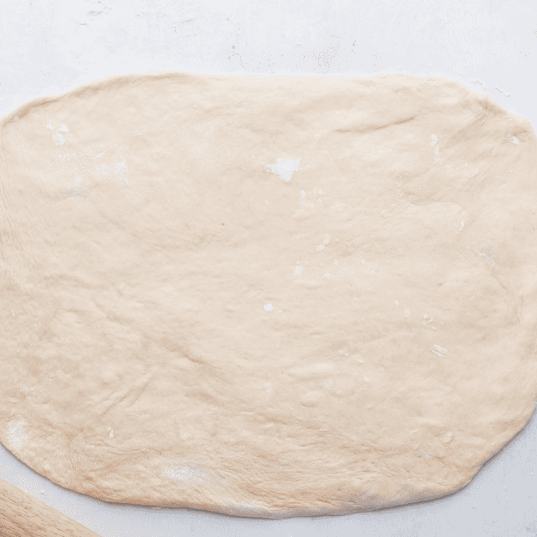 Trader Joe's pizza dough rolled into a rectangle on a floured surface, ready for cutting.