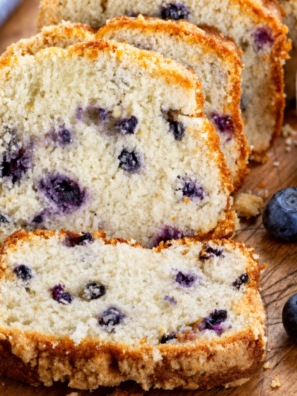 Sliced air fryer blueberry bread on a wooden board showing blueberries in the crumb
