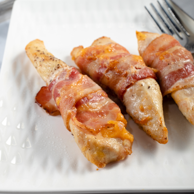 Air fryer bacon wrapped chicken stuffed with melted cheese and wrapped in crispy bacon on a serving plate