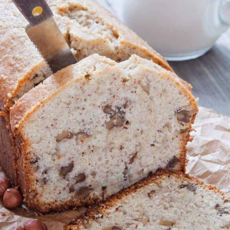 Slice of Air Fryer Cinnamon Walnut Pound Cake on a white plate, showing moist texture and crunchy cinnamon walnuts on top
