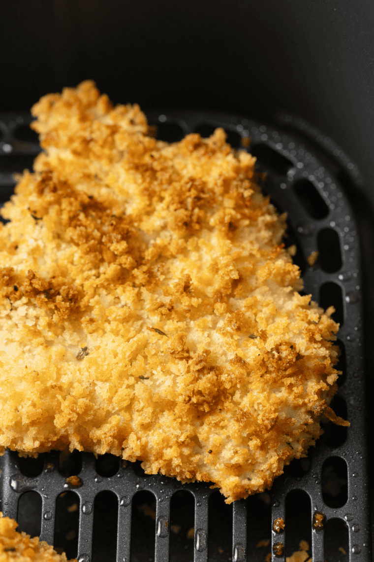 Golden, crispy air fryer frozen haddock served on a plate with lemon wedges and garnish.