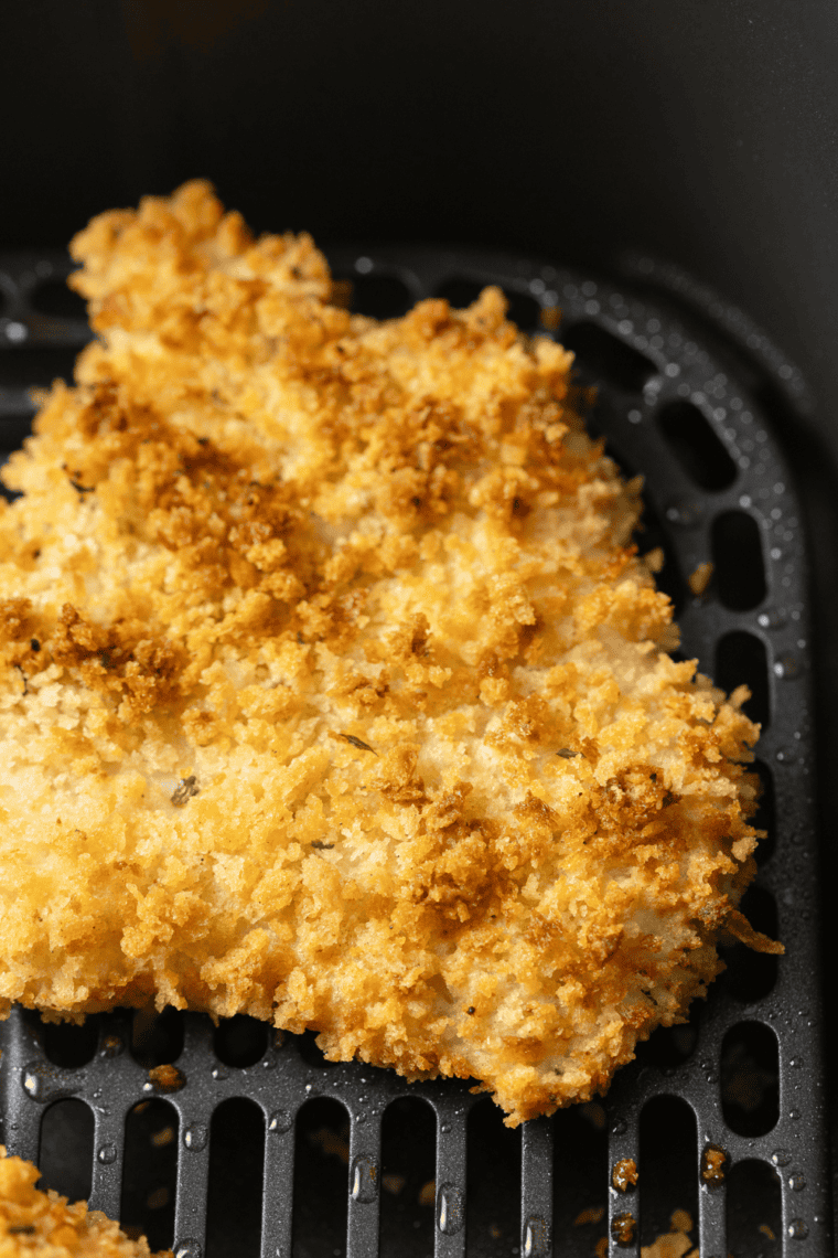 Crispy air fryer haddock served on a plate with lemon wedges and tartar sauce.