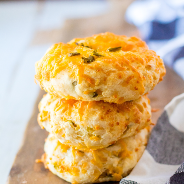 Four freshly air-fried jalapeño cheddar bagels with crispy golden cheese tops cooling on a wire rack