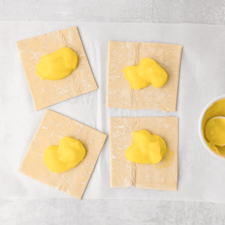 Spreading lemon curd onto puff pastry squares for turnovers."