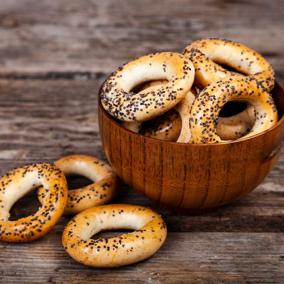 A plate of freshly baked poppy bagels arranged neatly on a white dish.