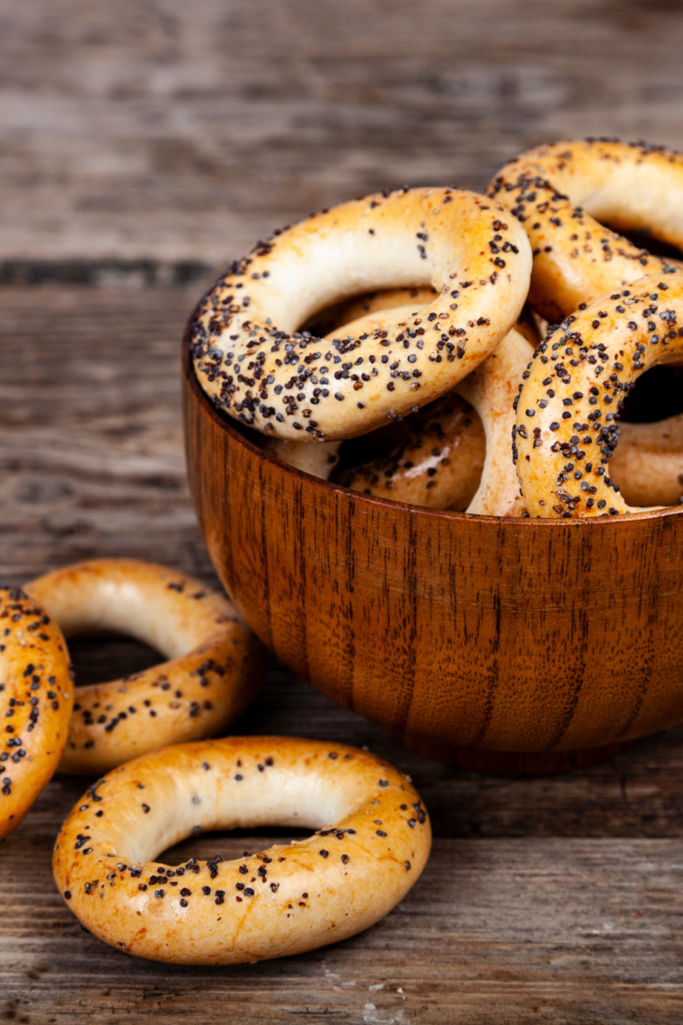 A bowl filled with freshly baked poppy bagels, showcasing their golden-brown crust and sprinkled poppy seeds.