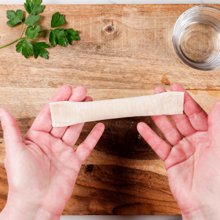 Rolling the wrapped mozzarella sticks and placing them on a greased air fryer basket or tray.