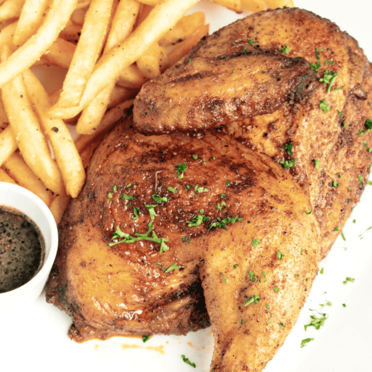 Cracker Barrel Herb Roasted Chicken golden brown in a platter with herbs on it.