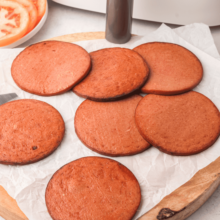 Two slices of air fried bologna on a white plate showing crispy browned edges