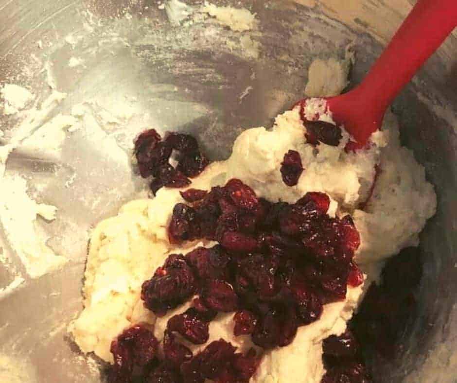 Mixing flour, Greek yogurt, and dried cranberries to create cranberry bagel dough