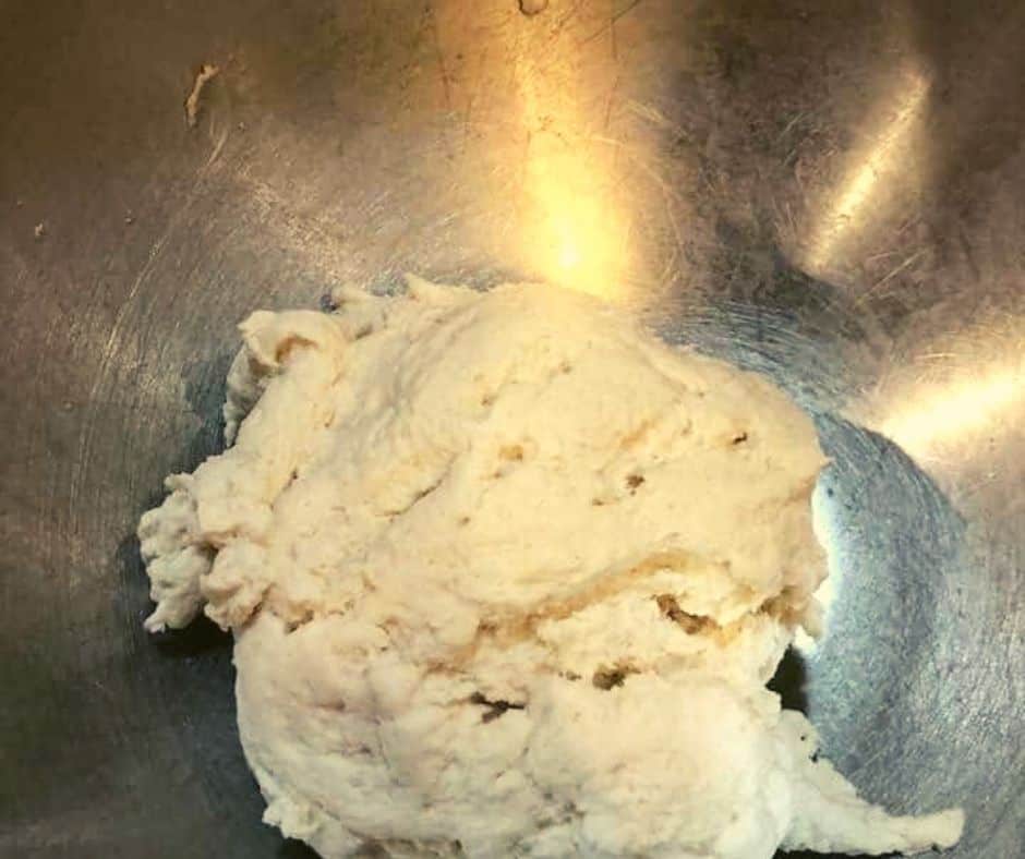 Combining Greek yogurt and self-rising flour to make bagel dough in a bowl.