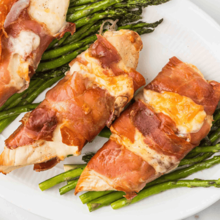 Golden brown air fryer chicken saltimbocca wrapped in prosciutto with sage, served with roasted asparagus and shallots