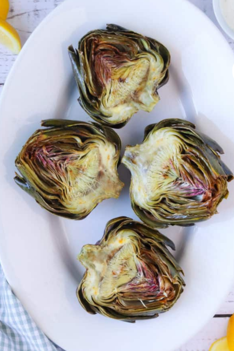 Crispy air fryer artichokes on a plate showing tender hearts and golden leaves