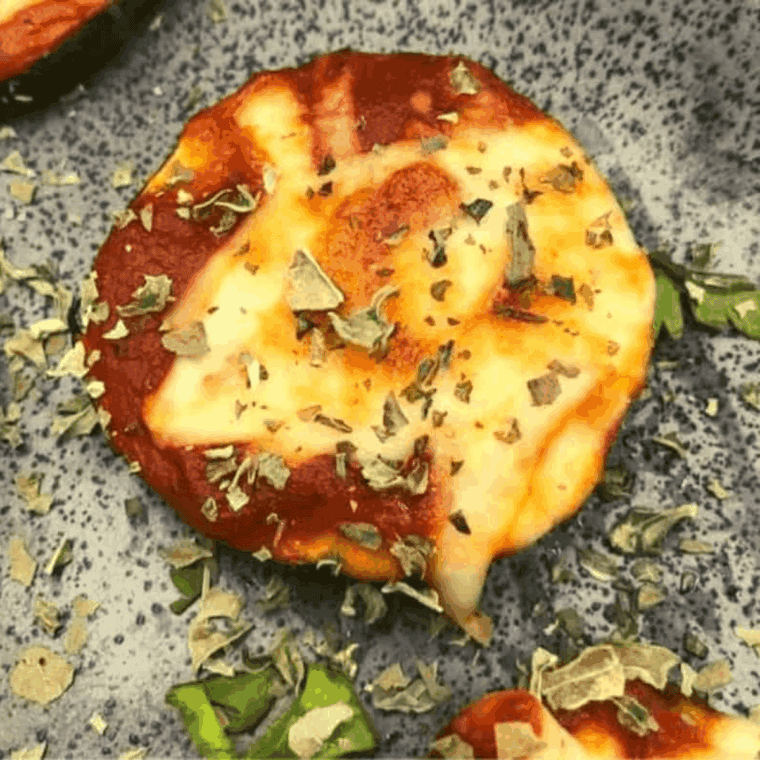 Air fryer zucchini pizza bites with melted mozzarella and pepperoni on a white plate