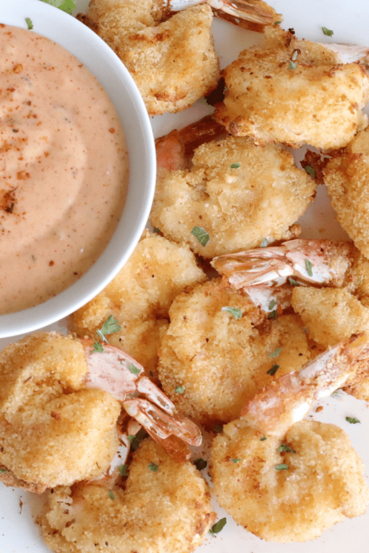 Golden crispy southern fried shrimp served on a plate with lemon wedges and dipping sauce.