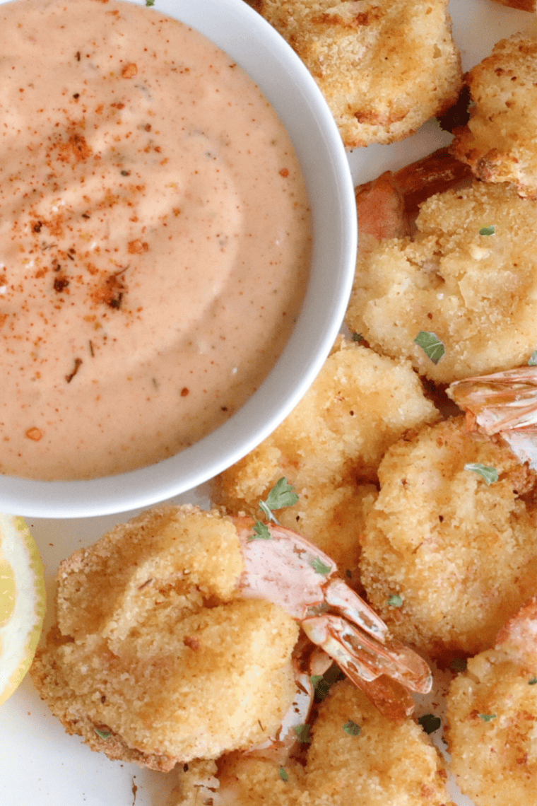 Golden crispy southern fried shrimp served on a plate with lemon wedges and dipping sauce.