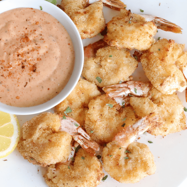 Fried golden shrimp on paper towels to drain oil, served with lemon wedges.
