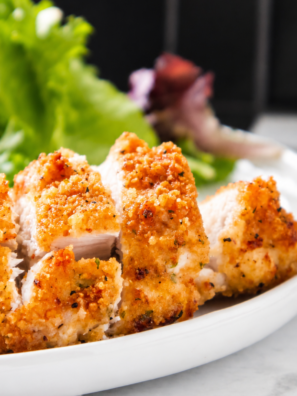 Air fryer chicken costoletta on a white plate, drizzled with lemon cream sauce and topped with chopped parsley