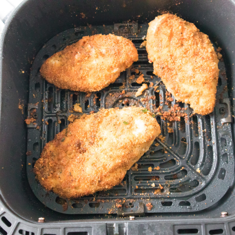 Three golden brown air fryer chicken costoletta cutlets finished in the air fryer basket.