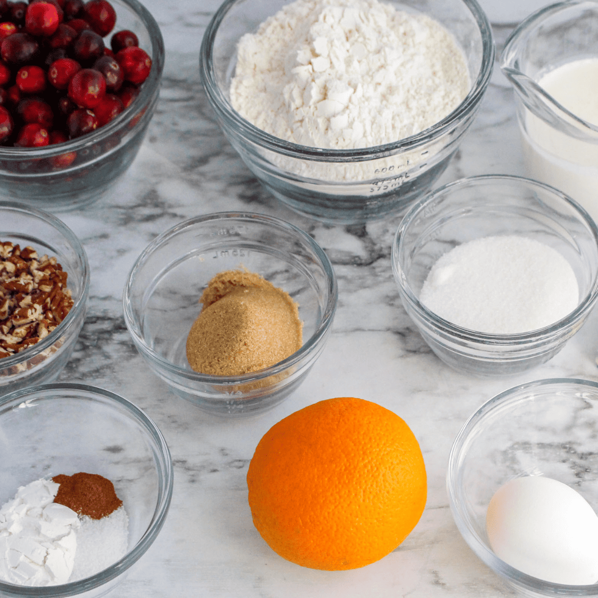 Ingredients for cranberry orange scones: flour, butter, cranberries, orange, cream and sugar