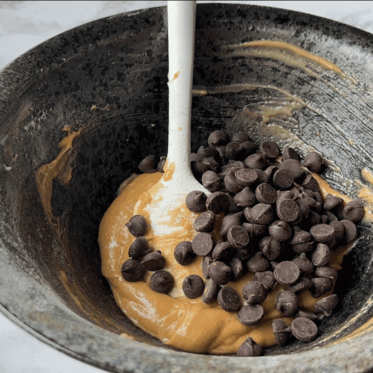 Folding wet ingredients and chocolate chips into muffin batter