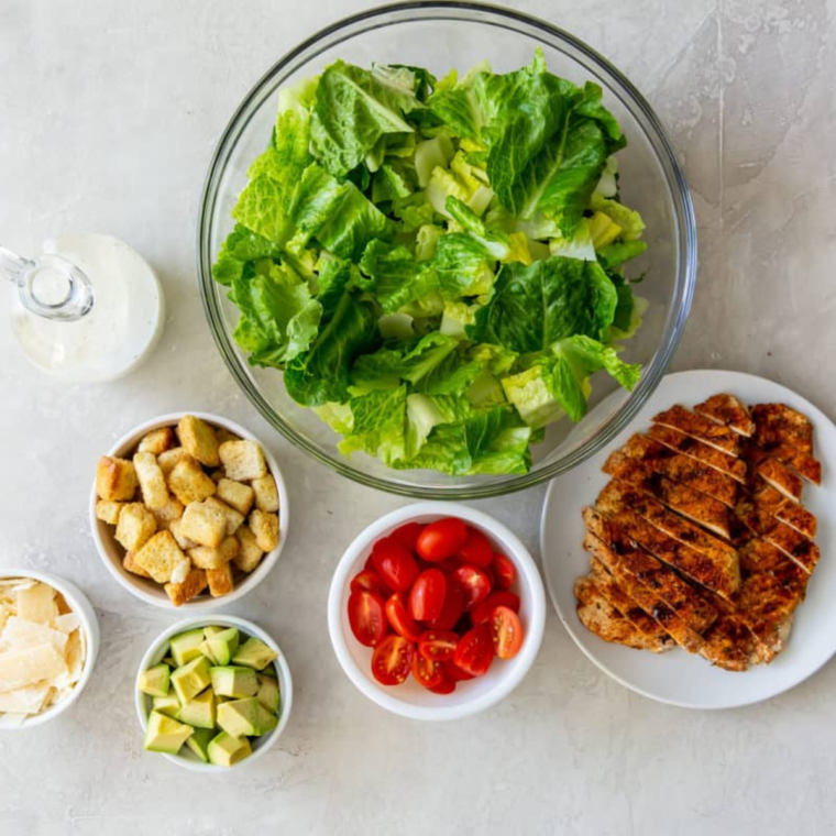 Ingredients for Air Fryer Grilled Chicken Caesar Salad laid out on a kitchen counter.