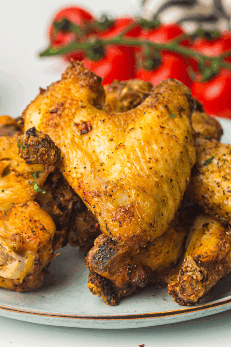 Crispy air fryer chicken wings coated in honey mustard sauce, garnished with parsley and served on a white plate.