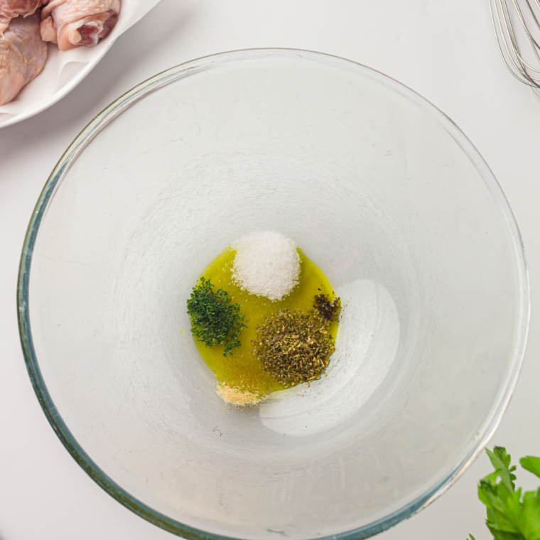 Kosher salt, black pepper, and garlic powder being sprinkled over raw chicken thighs