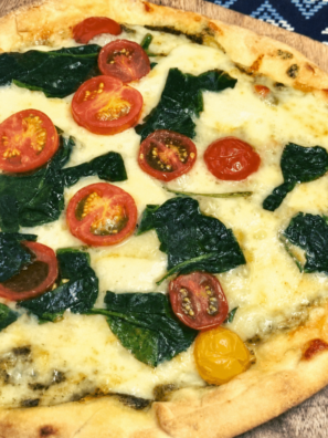 Sliced pesto spinach naan pizza on a wooden cutting board