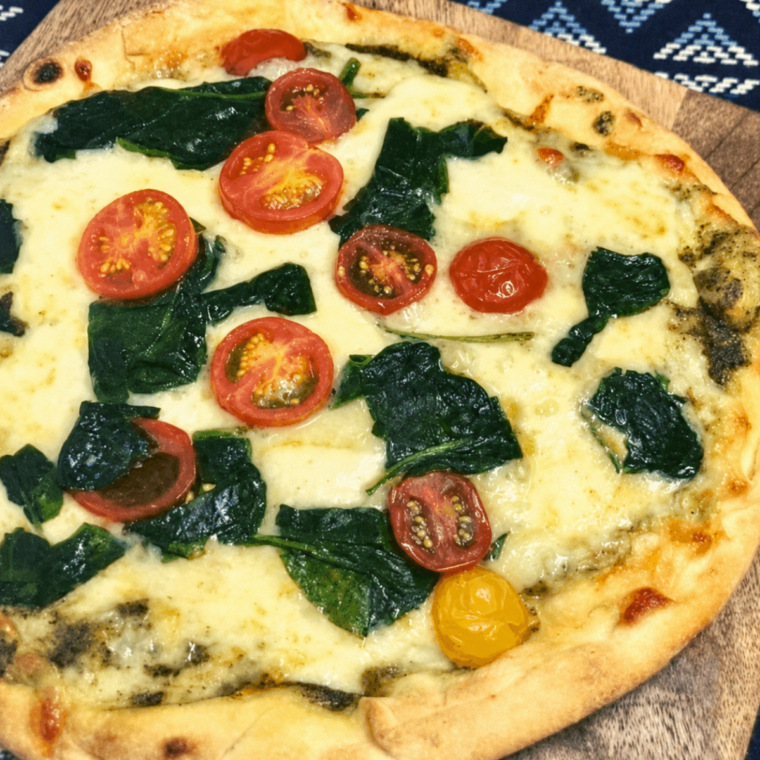 Sliced pesto spinach naan pizza on a wooden cutting board