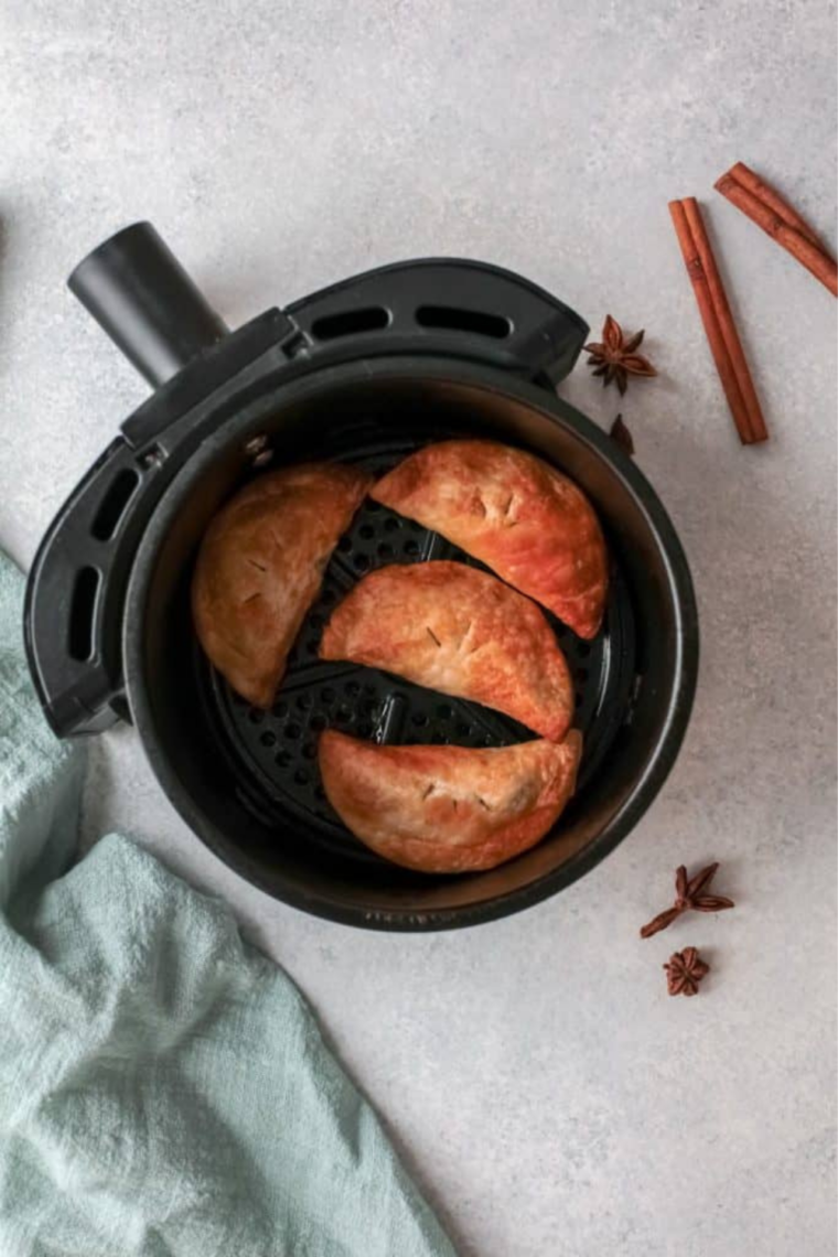 Plate of golden brown Easy Air Fryer Pumpkin Hand Pies with flaky crusts and warm spiced pumpkin filling.